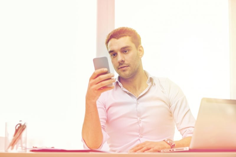 man looking at mobile app and writing business plan
